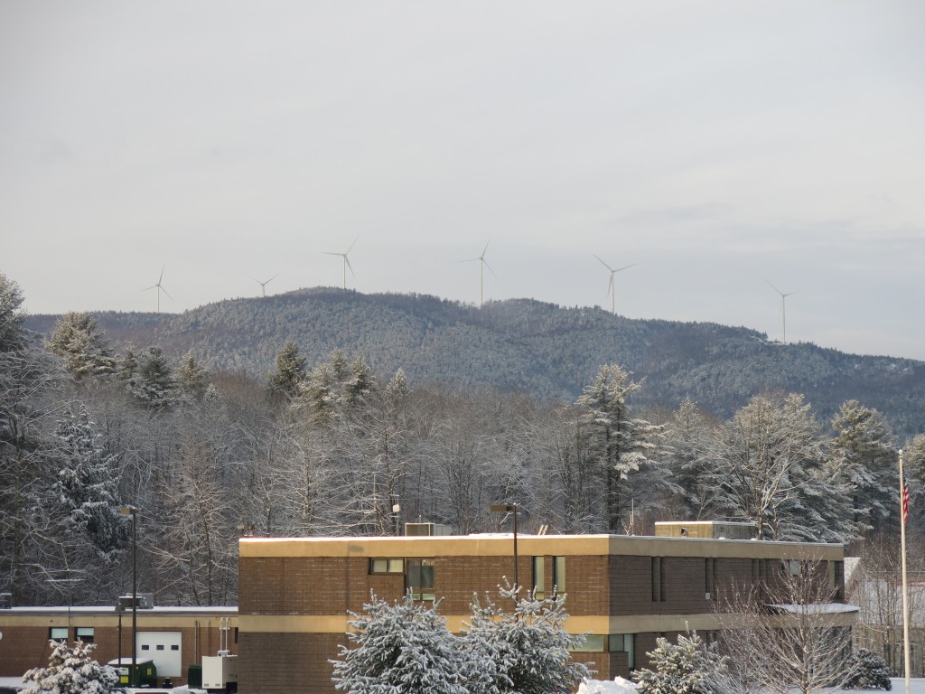 NHEC solar-powered headquarters campus in Plymouth. Wind turbines of the Groton Wind Farm, not owned by NHEC, are in the background. 