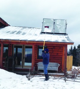 Cleaning off roof-mounted Solar Hot Water Panels with pole extended. 
